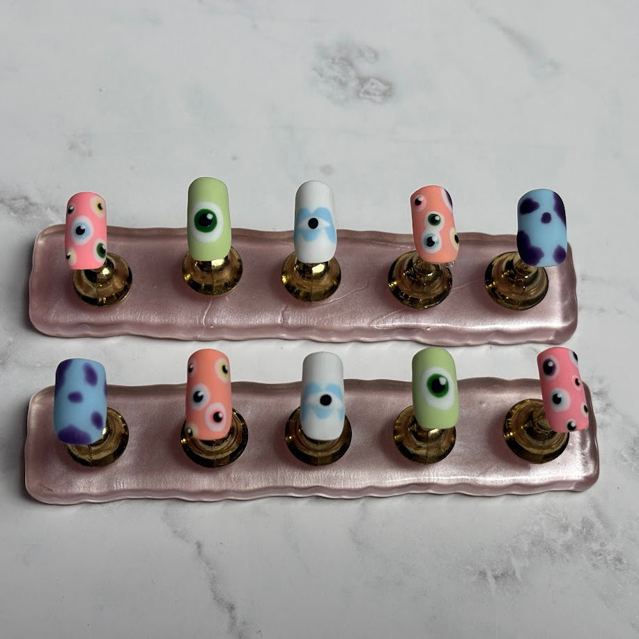 Set of colorful nail art display on a pink stand against a marble background