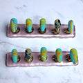 Set of nail art designs on a pink stand against a marble background