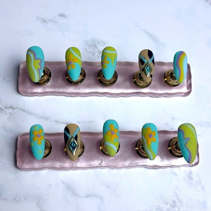 Set of nail art designs on a pink stand against a marble background